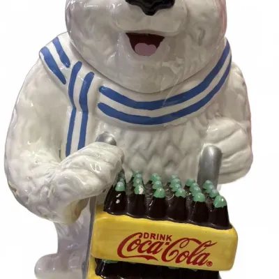 Vintage Coca-Cola ceramic polar bear cookie jar featuring the bear pushing a hand truck filled with yellow Coca-Cola bottle crates.