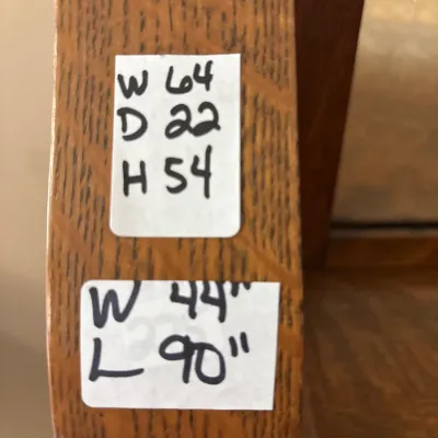 Handwritten dimension tags attached to a light oak wooden furniture piece.