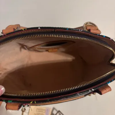 Interior view of a Louis Vuitton Monogram Multicolore Alma handbag, featuring light suede lining, an interior slip pocket, and natural...