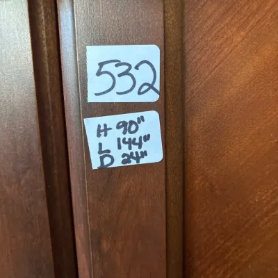 Close-up of a wooden cabinet door with estate sale lot sticker 532 showing dimensions of 90 inches high by 144 inches long by 24 inches...