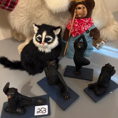 Collection of decorative animal figurines and plush toys, including yoga-posing bear figurines, a black-and-white plush cat, and a...