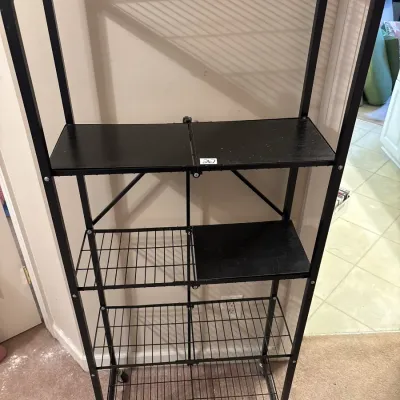Black metal five-tier folding shelving unit on caster wheels, featuring removable solid shelf inserts.