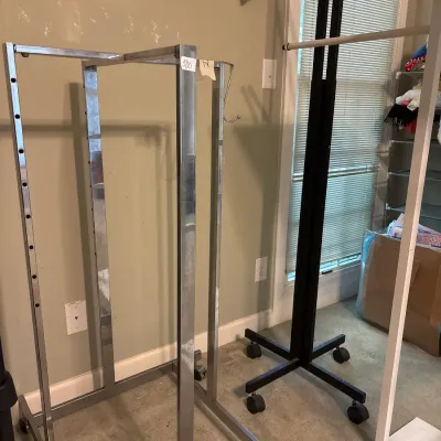 Selection of commercial metal clothing display racks, including chrome and black rolling garment stands.