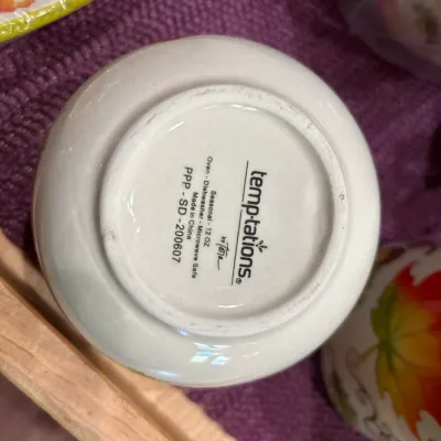 Underside of a Temp-tations by Tara 12 oz seasonal ceramic dish showing the manufacturer stamp and care instructions.