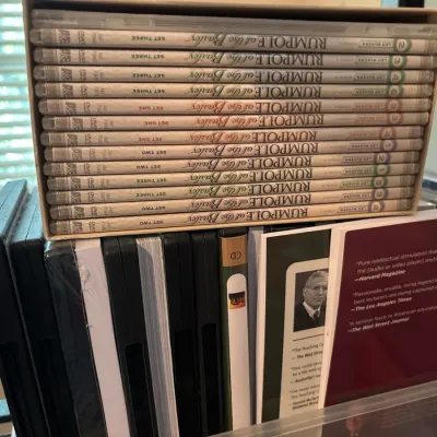A collection of media including a boxed set of 'Rumpole of the Bailey' DVDs sitting atop a bin of assorted CDs and audiobooks.