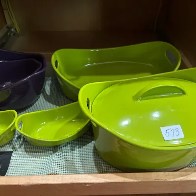 Collection of modern Curtis Stone Dura-Pan nonstick cookware, including lime green oval baking dishes, a covered Dutch oven, and a nested...