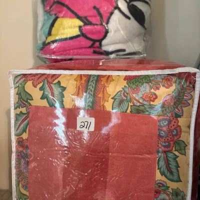 Two packaged bedding sets in plastic zippered storage bags, featuring a floral pattern comforter labeled with lot number 271 and a...
