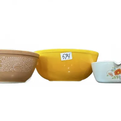 Collection of three vintage Pyrex mixing and pouring bowls, including a tan floral motif bowl, a solid yellow bowl, and a small floral...