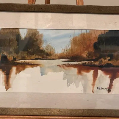 Original framed watercolor landscape painting depicting a serene river scene, signed by artist Betty Zoe Miller in the lower right corner.