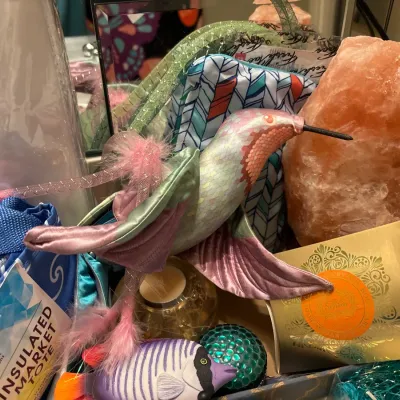 Collection of decorative household items including a Himalayan salt lamp, fabric hummingbird ornament, fish figurine, and an insulated...
