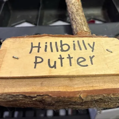 Novelty "Hillbilly Putter" golf club with a rustic wood branch handle and log mallet head.