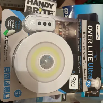 SensorBrite Over Lite Ultra LED puck light in original blister packaging, featuring wireless remote and motion sensor.