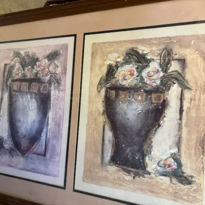Framed dual art prints depicting stylized floral arrangements in dark vases, presented under glass with a double mat in a wood frame.
