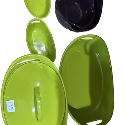 Collection of modern green and eggplant purple ceramic baking dishes, including oval casseroles and serving bowls with built-in handles.