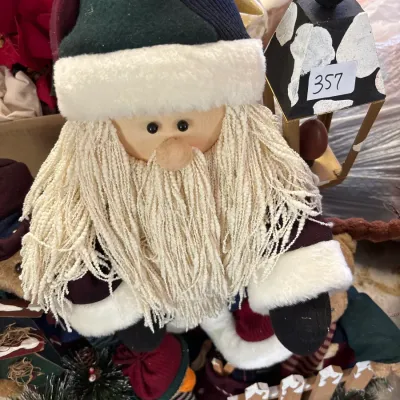 Handmade Santa Claus figure featuring a yarn beard, plush trim, and knit hat, displayed alongside festive holiday decor.