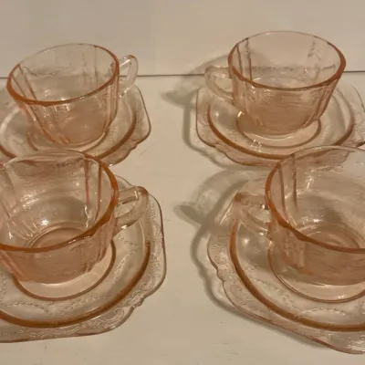 Set of four pink Depression glass teacups and matching saucers featuring a delicate molded floral pattern, circa 1930s.