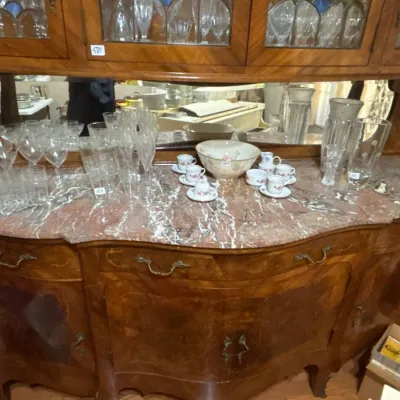 French Provincial style inlaid wood hutch with a marble-top sideboard, mirrored back, and glass-front upper cabinet, filled with...