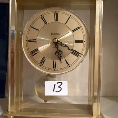 Bulova brass and glass mantel clock with Roman numerals and a swinging pendulum.