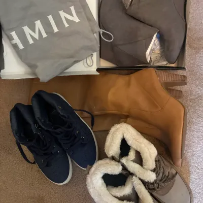 Collection of women's footwear including tan high-heeled boots, blue high-top sneakers, faux fur-trimmed winter boots, and grey...