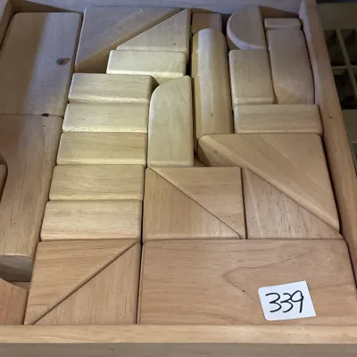 Vintage set of natural wooden building blocks arranged neatly inside a matching wooden storage tray.