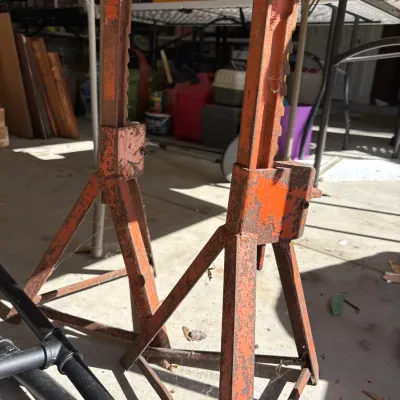 Pair of vintage heavy-duty orange steel jack stands showing cosmetic rust and wear.