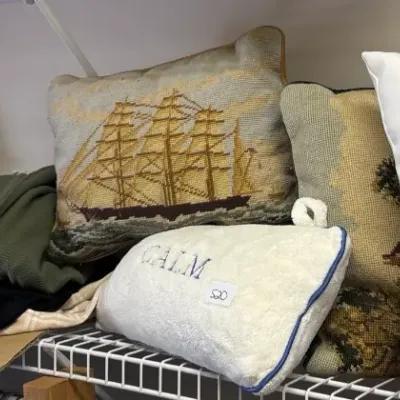 Assortment of decorative throw pillows, including needlepoint sailing ship design, botanical iris print, and a pink flamingo...