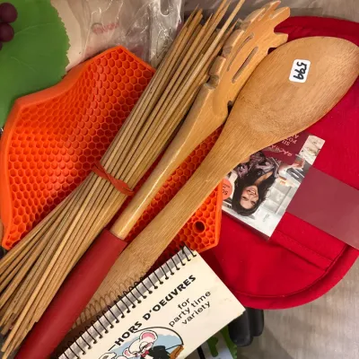 Collection of kitchen items including bamboo serving utensils, skewers, silicone hot pads, and a vintage hors d'oeuvres recipe notepad.
