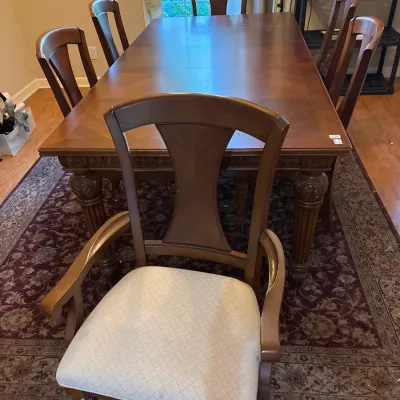 Traditional dark wood dining room set including a rectangular extension table with carved legs and six matching splat-back chairs, one...