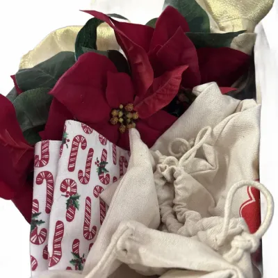 Assortment of holiday decor and gift wrapping items, including artificial red poinsettia flowers, gold sheer ribbon, candy cane patterned...