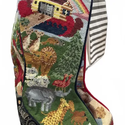 Handcrafted needlepoint Christmas stocking featuring a Noah's Ark motif with various animals, a rainbow, and dark blue piping.