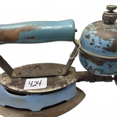 Antique blue gas/kerosene sad iron with attached fuel tank, showing heavy patina and paint wear.
