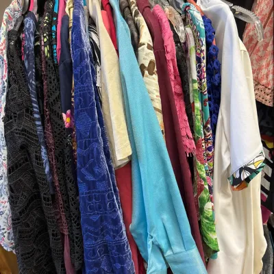 Selection of women's vintage and contemporary clothing on clear plastic hangers, including pattern prints, velvet pieces, and lace...