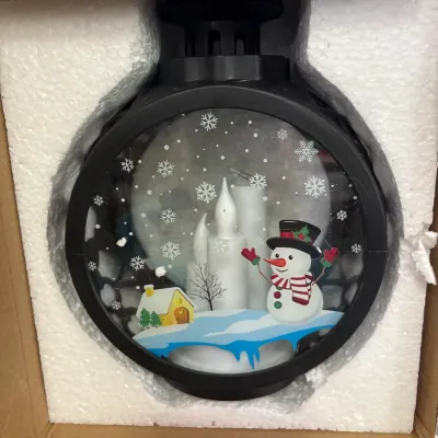 Novelty Christmas snow globe lantern featuring a snowman and house scene, brand new in its original styrofoam packaging.