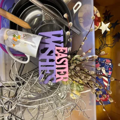 Plastic storage bin filled with an assortment of household items, holiday decor, an Easter mug, and kitchen strainers.