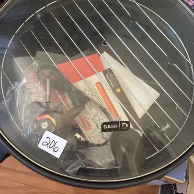 Dash electric skillet with glass lid, wire rack, power cord, and original paperwork contained inside.