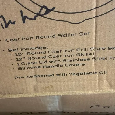 Boxed pre-seasoned cast iron round skillet set, including a 10-inch grill skillet, a 12-inch skillet, glass lid, and silicone handle covers.