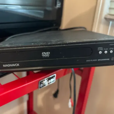 Magnavox DP100MW8B DVD player sitting on a red Origami brand shelving unit.