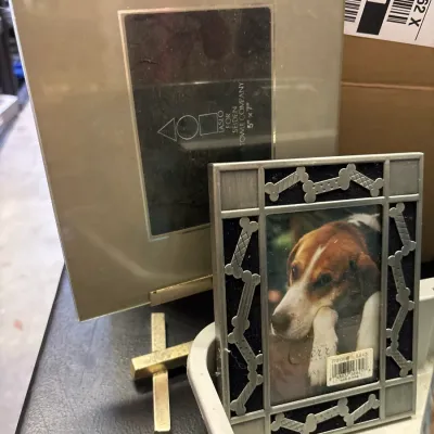 Pair of picture frames, including a Laslo for Seiden Towle Company 5x7 frame and a pewter dog bone motif frame with a stock photo.