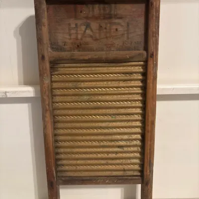 Vintage Dubl Handi brass-front washboard with a wooden frame and faded stenciled branding at the top.