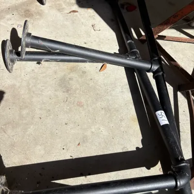 Pair of black industrial pipe wall shelves or clothing rack frames with mounting flanges.