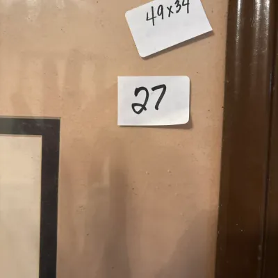Close-up of a framed artwork showing handwritten stickers with dimensions 49x34 and lot number 27.