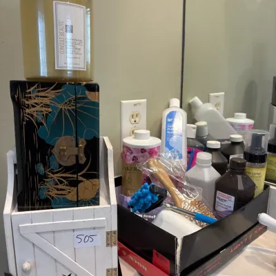 Assortment of bathroom toiletries and vanity storage, including Consult Beaute body creme, a Asian-style lacquered box, and various...