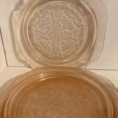Pair of Depression-era pink molded glass plates with intricate floral and scrollwork detailing.