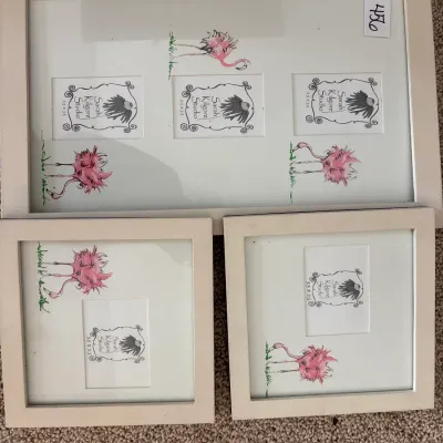 Set of three white wooden picture frames by Sarah Kilgore Studio featuring flamingo illustrations around the matted openings.