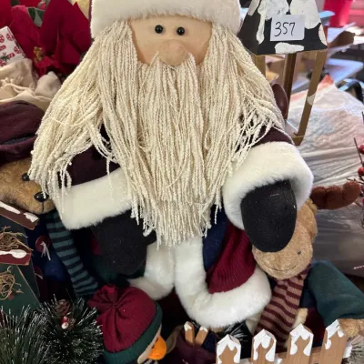 Rustic plush Santa figure featuring textured yarn beard, fabric suit, and accent animals including a penguin and reindeer.