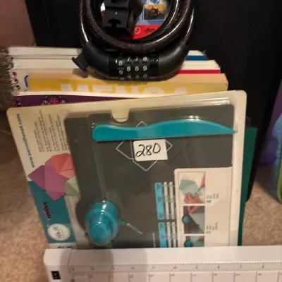 Collection of crafting supplies including a paper trimmer and We R Memory Keepers envelope punch board, alongside books and a bicycle...