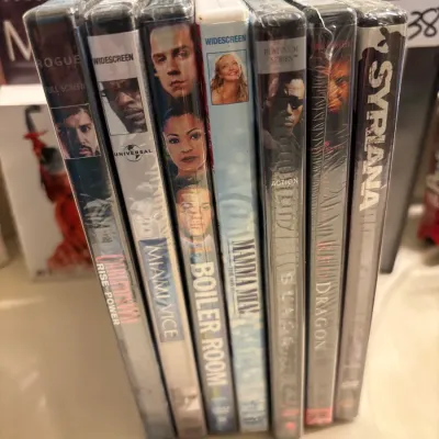 Stack of sealed DVD movies from the 2000s, including titles such as Miami Vice, Boiler Room, Mamma Mia!, Blade II, Red Dragon, and Syriana.