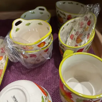 Collection of Temp-tations autumn harvest ceramic tableware, including mugs and small handled bowls featuring a leaf and pumpkin motif.