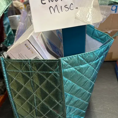 Metallic teal quilted tote bag filled with miscellaneous boxed electronics.