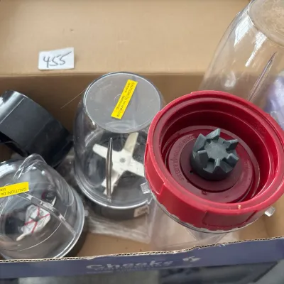 Box lot of personal blender accessories, including clear plastic cups, blade attachments, and lids.